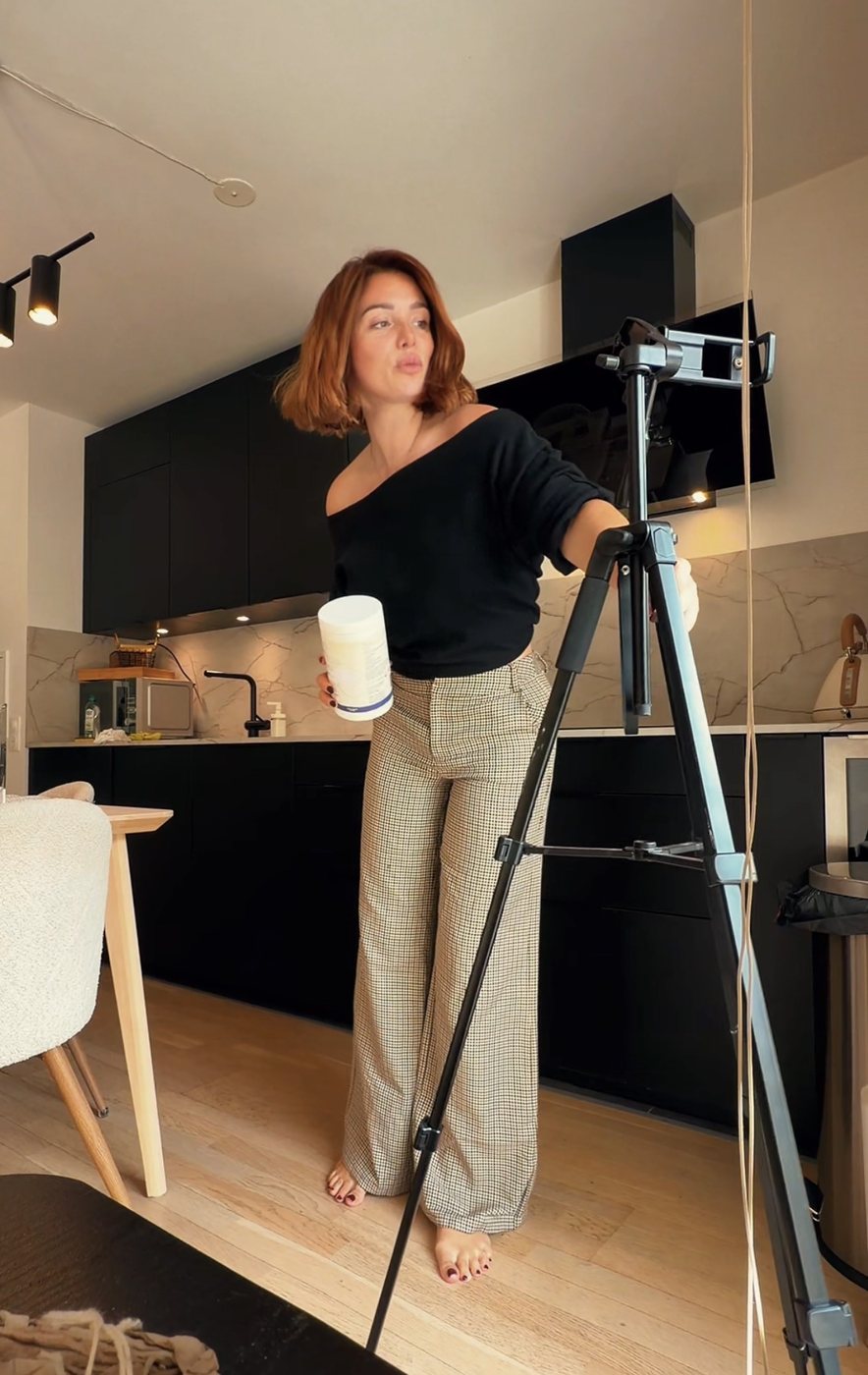 Kathleen règle son trépied dans sa cuisine avant un tournage UGC, un produit à la main